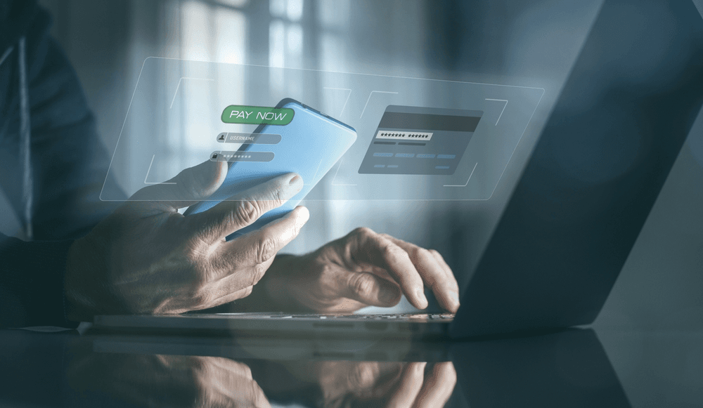 A customer confirming a payment on their phone beside a laptop